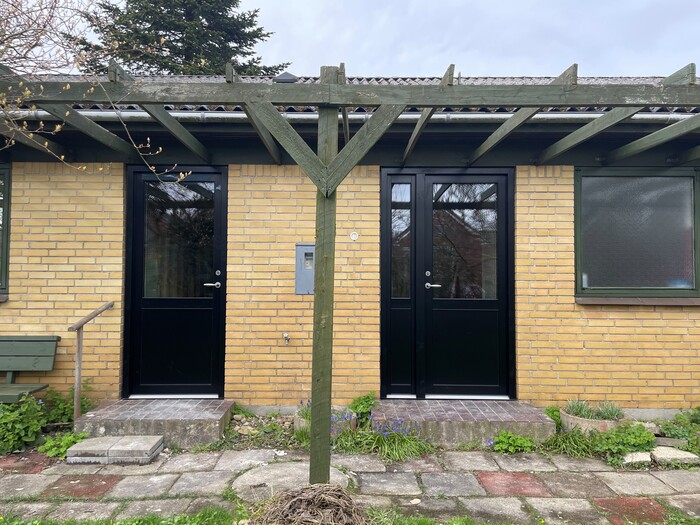 Montering af nye vinduer og døre i Midtjylland - facade med to sorte hoveddøre i moderniseret bolig.